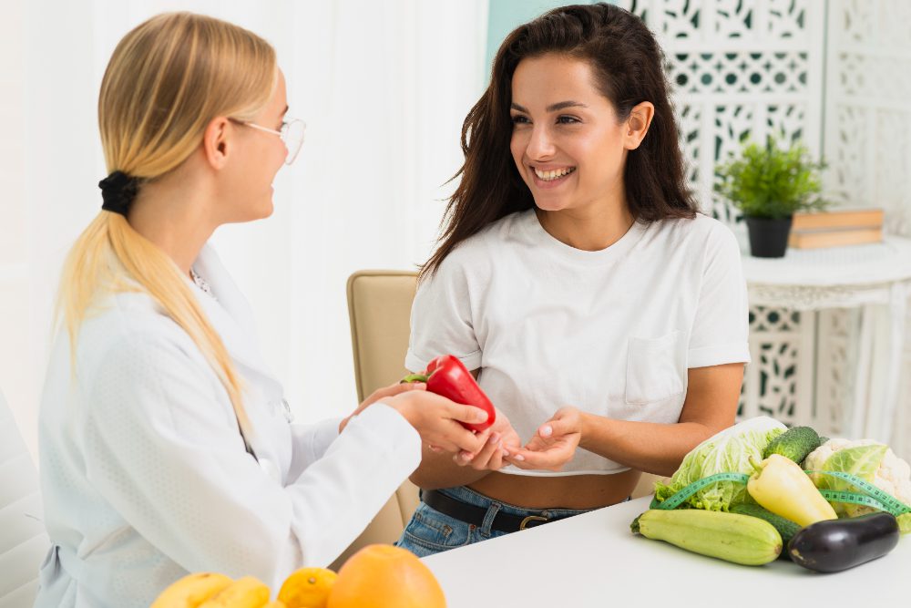 Nutritionists handing a pepper to a client with various vegetables on the table